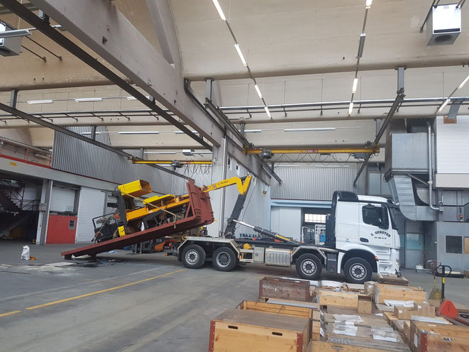 Ein weisser Lastwagen von Gerster Recycling steht am Abbruch und der Demontage von Industrieanlagen. Es ist ein Kran mit Greifer und Logo von Gerster Recycling zu sehen. Das Bild zeigt einen Transport und Muldenservice.