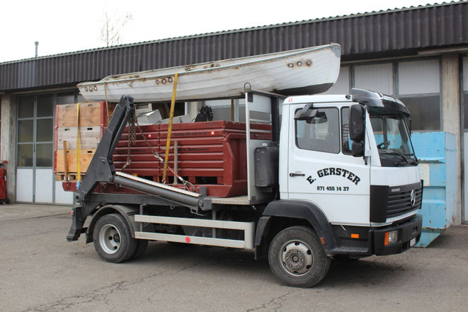 Ein weisser Lastwagen von Gerster Recycling steht am Abbruch und der Demontage von Industrieanlagen. Es ist ein Kran mit Greifer und Logo von Gerster Recycling zu sehen. Das Bild zeigt einen Transport und Muldenservice.
