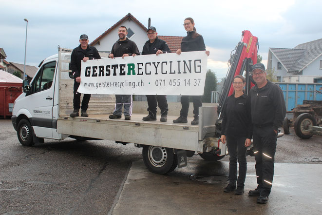 Ein weisser Lastwagen von Gerster Recycling steht an der Annahmestelle u. Altmetallhandel. Im Hintergrund sind mehrere grosse rote Abfallcontainer mit dem Logo von Gerster Recycling zu sehen. Das Bild zeigt einen Recycling- und Abfallentsorgungsbetrieb.