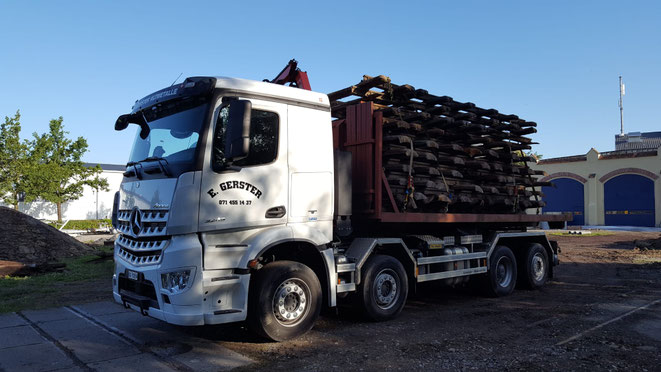 Ein weisser Lastwagen von Gerster Recycling steht am Abbruch und der Demontage von Industrieanlagen. Es ist ein Kran mit Greifer und Logo von Gerster Recycling zu sehen. Das Bild zeigt einen Transport und Muldenservice.