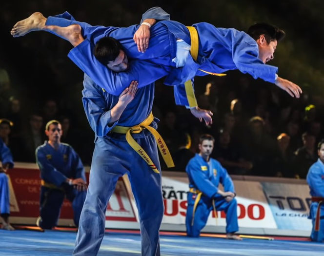Kämper des Vovinam Viet Vo Dao machen einen Vorführung. Ein Kämpfer wehrt sich mit einem Scherentrittsprung zum Kopf gegen einen Angreifer.