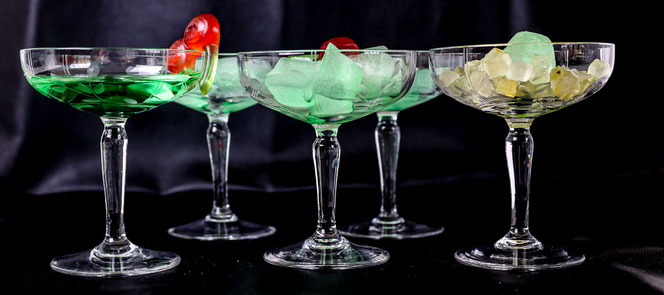 Vintage-Cocktail-Gläser  gefüllt mit grüner Flüssigkeit oder Eiswürfel und gelb-grünem Zitronat.