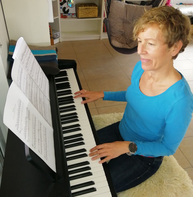 Christine Harnik sitzt am Klavier und spielt nach Noten in einem Wohnraum.