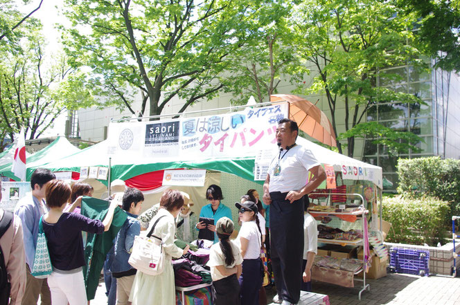 「夏は涼しい タイパンツ！」 軽快で軽やかな語り口で タイの服飾雑貨屋さんの方が実演販売。立ち止まるお客さん。「第14回 タイ・フェスティバル2013年 東京・代々木」の会場写真