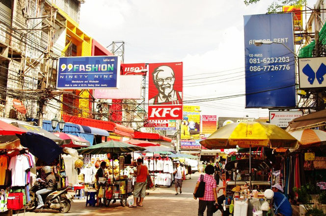 KFC ケンタッキー カオサン店 カーネルサンダースのイラスト看板がタイのカオサンにも。写真両サイドにはパラソルを広げる露天と屋台が広がる。雑多な東南アジアの光景。左側にはごちゃごちゃとした電線も【バンコク ピクチャー】  タイ王国の首都・バンコクの旅行（出張）写真ブログ