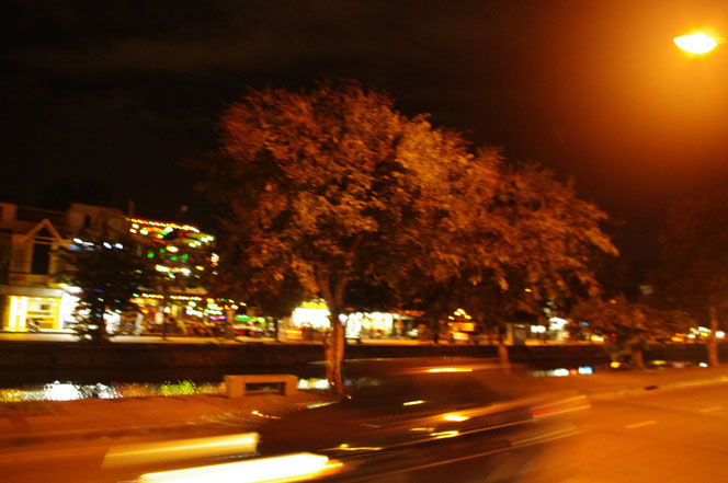 チェンマイ サタデーマーケットの帰り道。夜のチェンマイ市街。スピードを出して走り去る車の写真。高速で走り抜けたため、写真も車がブレてしまっている。写真奥にはチェンマイの水堀も見える。[タイ・チェンマイ旅行（出張）写真ブログの画像]