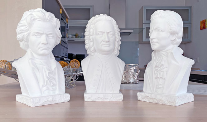 Drei große Büsten der Komponisten Beethoven, Bach und Mozart stehen auf einer Kücheninsel im Halbkreis. Im Hintergrund sieht man eine Deko-Schale und Anteile einer Küche.