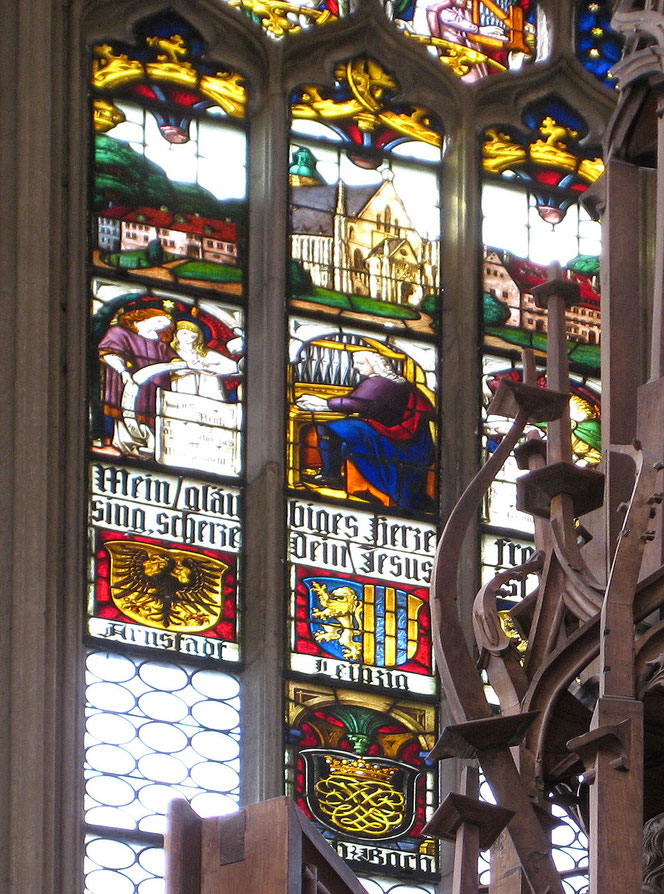 Ein wundervolles, buntes Kirchenfenster in der Thomaskirche in Leipzig. In der Mitte sitzt Bach an der Orgel und spielt.