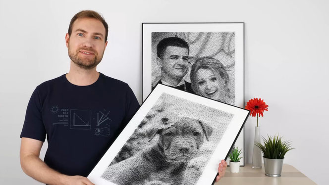 André Gall präsentiert ein Fadenbild mit einem Hund zum Betrachter. Auf einem Schränkchen steht im Hintergrund ein zweites Fadenbild mit einem jungen Paar. Rechts daneben ist eine rote Gerbera in einer Vase. André lächelt zum Betrachter.