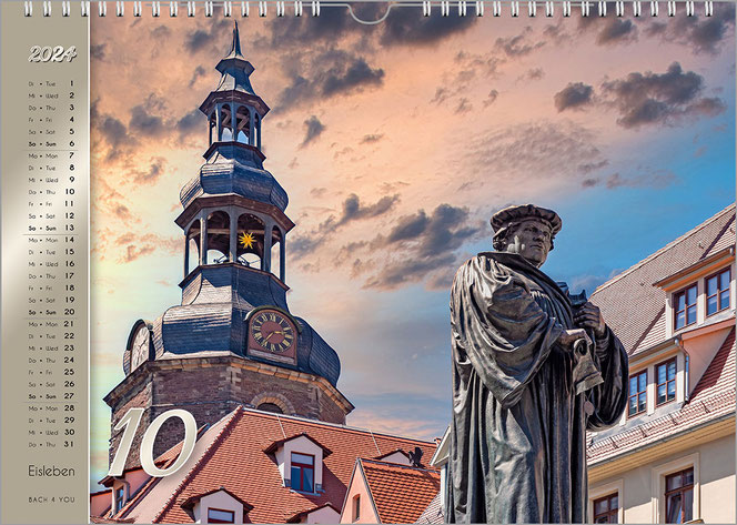 Es ist ein verfremdetes Foto auf diesem Luther-Kalender-Monatsblatt. Links ist ein riesiger Glockenturm, rechts ist das Luther-Denkmal. Am linken Rand ist das Kalendarium auf goldenem Grund.
