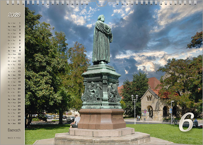 Ein Foto des Luther-Denkmals in Eisenach. Es ist ein Monatsblatt im Luther-Kalender. Es steht in einer Parkanlage. Links ist auf goldenem Untergrund das Kalendarium.