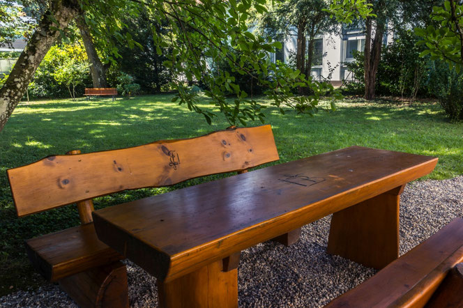 Eine Sitzgruppe aus Baumstämmen geschnitten mit Blick in den Gartenpark