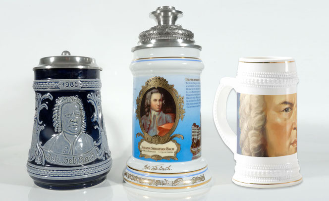 Three Bach beer steins stand on a white underground and in front of a white background. On the left is the dark blue/light gray Bach beer stein from 1985, in the middle is the noble, tall beer stein from the year 2000, on the right is a current beer stein