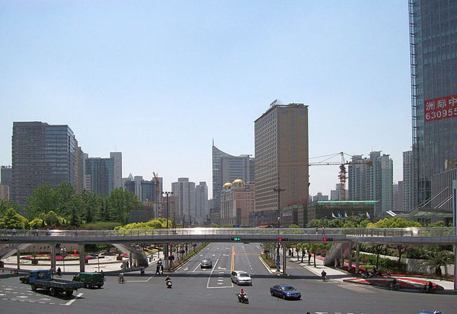 An intersection with an overpass in Shanghai, China. In the background, you can see some skyscrapers.