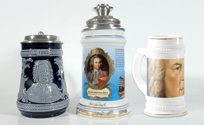 In front of a white background and on a white background, there are three Bach beer steins. On the left is a dark blue/light gray one. In the middle is a very elaborate, tall one. On the right is an actual white beer stein. All three show Bach's portrait.