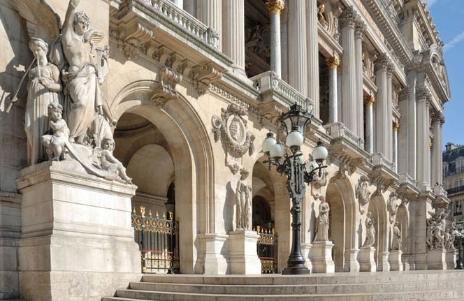 The front view of the Paris Opera in the sunshine. The photo was taken at an angle from the front. Several plaques depict composers.