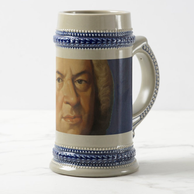 A current Bach beer mug in the color gray. There is a blue decorative band at the top and on the handle. Opposite the handle is a colorful portrait of Bach, once painted by Haußmann.