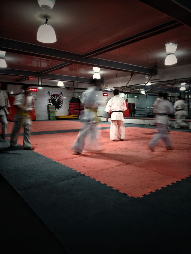 Karate-Schüler trainieren in einer Sporthalle und laufen im Kreis, um sich zu erwärmen und um sich auf das Training vorzubereiten.