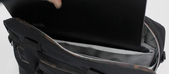 Laptop being placed into an ETUBY business bag with a protective compartment