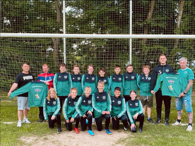 Sven Biederstedt (Fa. Elektro Biederstedt, links) und Michael Zürner (Fa. Heizung-Sanitär-Zürner, rechts) überreichen dem Team die frisch bedruckten Trainingsanzüge