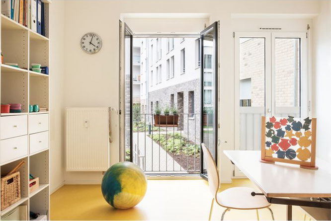 Heller Behandlungsraum mit Gymnastikball und offenem Blick in einen begrünten Innenhof einer Ergotherapiepraxis in Stuttgart.