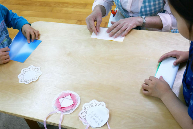 幼稚園児クラスの年長児が、モンテッソーリ活動で母の日のプレゼントにペンダントを製作。ペンダントにつけるカーネーションを折り紙で作っています。