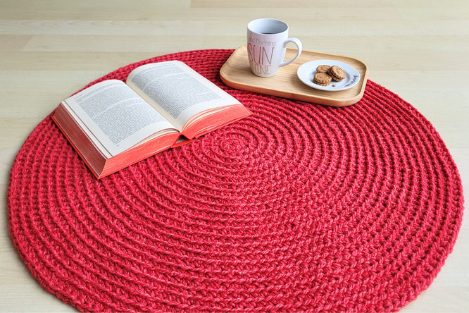 Ein gemuetlicher Haekelteppich mit einer Tasse Tee, Keksen und einem Buch