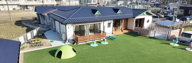 大分県日田市・朝日こども園の新園舎外観。令和7年5月完成。人工芝の広い園庭が広がる新しい保育施設　こども誰でも通園制度