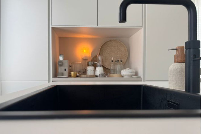 Witte keuken zwarte kraan en bruine woondecoratie in nis