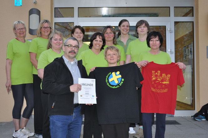 Barbara Adler erhält im April 2015 vom TSV-Vorstand Wolfgang Pfeiffer die Urkunde und das "Pluspunkt Gesundheit"-T-Shirt zur Verlängerung des Gütesiegels "Sport pro Gesundheit" in Awesenheit der "Spiel dich fit-Gruppe"überreicht. Foto: Rebhan