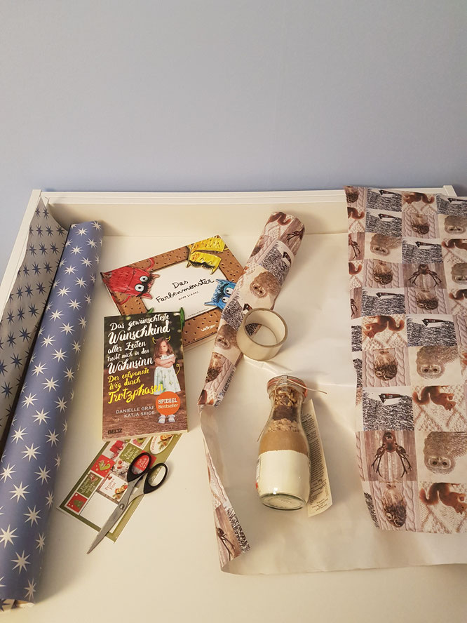 Weihnachtsgeschenke werden auf weißem Tisch verpackt. Geschenke-Guide für Mamas auf Patschehand.de.