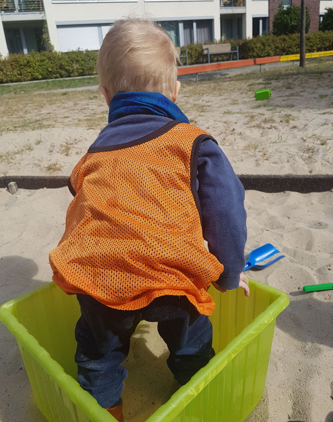 Kleinkind spielt im Sandkasten der Kita während der Eingewöhnung.