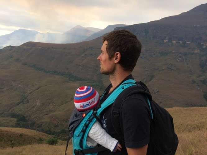 Frischgebackener Vater mit Baby in Komforttrage auf Reisen in Afrika.