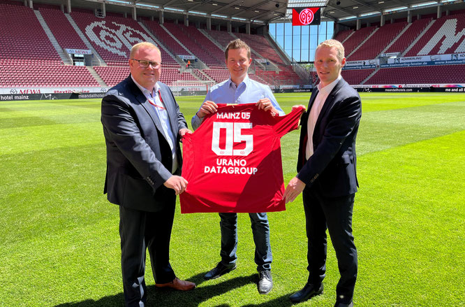 Symbolische Trikotübergabe in der MEWA-Arena: URANO-COO Sebastian Schmalenbach mit David Schössler (links, Leiter Vermarktung & Partnermanagement bei Mainz 05) und Martin Skrodzki, Associate Director und Teamleiter 1. FSV Mainz 05 bei Infront Germany.