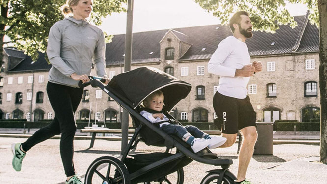 Eltern laufen mit Jogger-Kinderwagen
