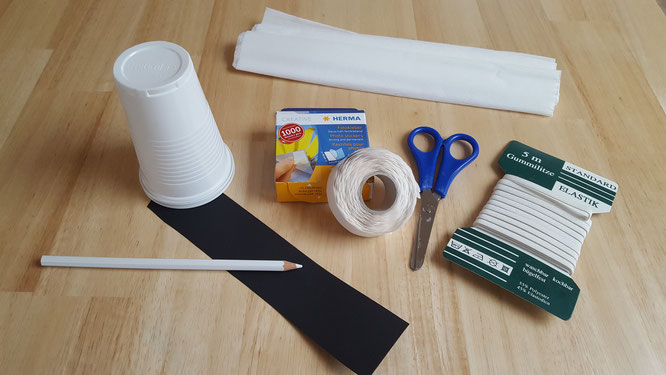 Das Material für ein Becher-Gespenst: Plastik-/Papp-Becher, Krepppapier, schwarzer Tonkarton, Gummiband