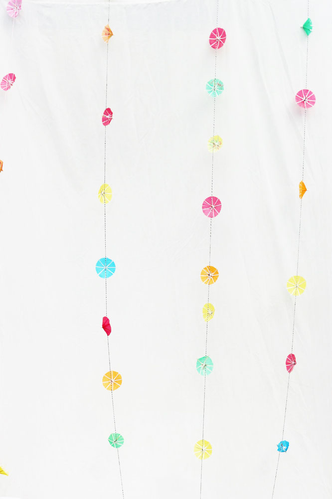 Bild: DIY Deko Girlande für die Party oder Hochzeit aus Cocktailschirmchen als Hintergrund für eine Fotoecke selber machen; Anleitung und Tipps vom DIY Deko und Partystyling Blog www.partystories.de