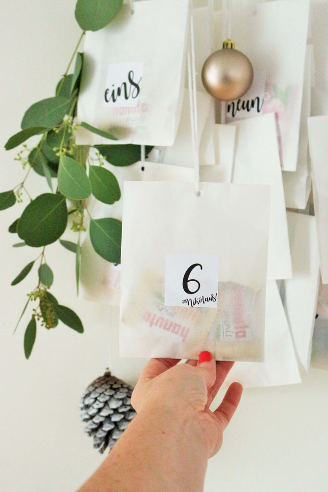 Bild: DIY Adventskalender Idee mit Kleiderbügel und Papiertüten, inklusive Freebie Zahlen zum ausdrucken im angesagten Lettering-Style; gefunden auf www.partystories.de