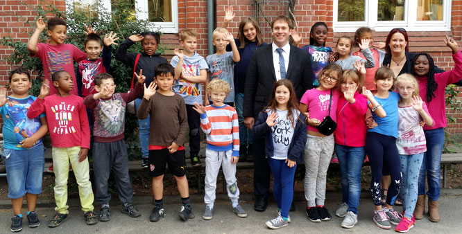 Bianca Neugebauer (Schulleiterin) und Michael Weinreich (MdHB) unringt von Schulkindern der Katholischen Bonifatiusschule Wilhelmsburg