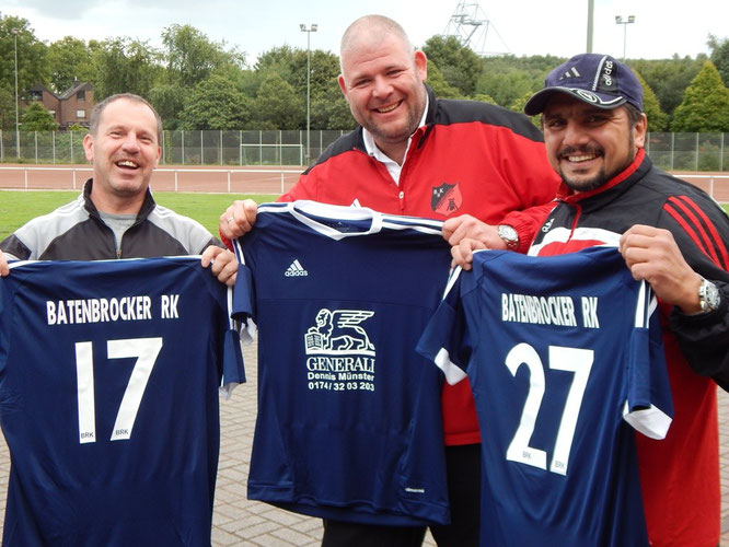 Dennis Münster (Mitte) präsentiert die neuen Trikots mit den Trainern der ersten Mannschaft Michael Goldberg (links) und Murat Memisoglu.