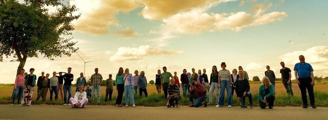 klangreich vocalensemble, eine gruppe steht vor einem feld ,darüber wolken