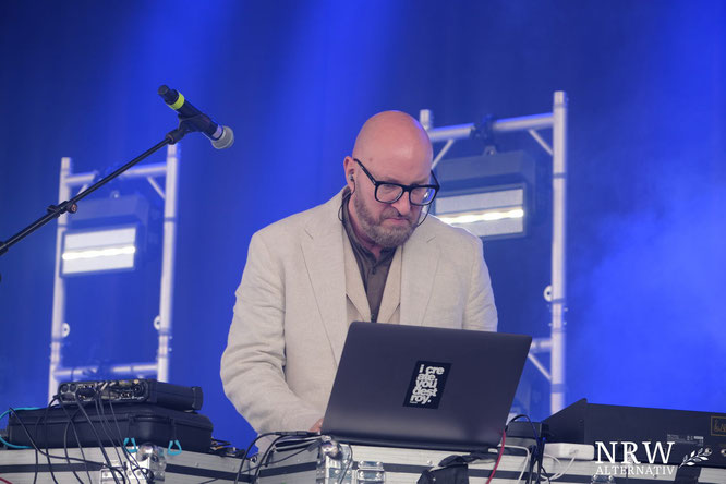 Ein Mann mit Brille und Glatze vor einem Laptop auf einer Bühne.