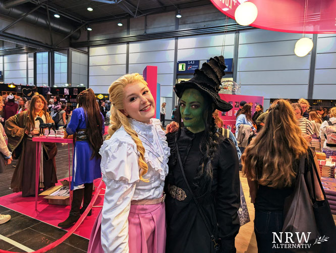 Zwei Cosplayerinnern auf der Leipziger buchmesse an einem Stand.