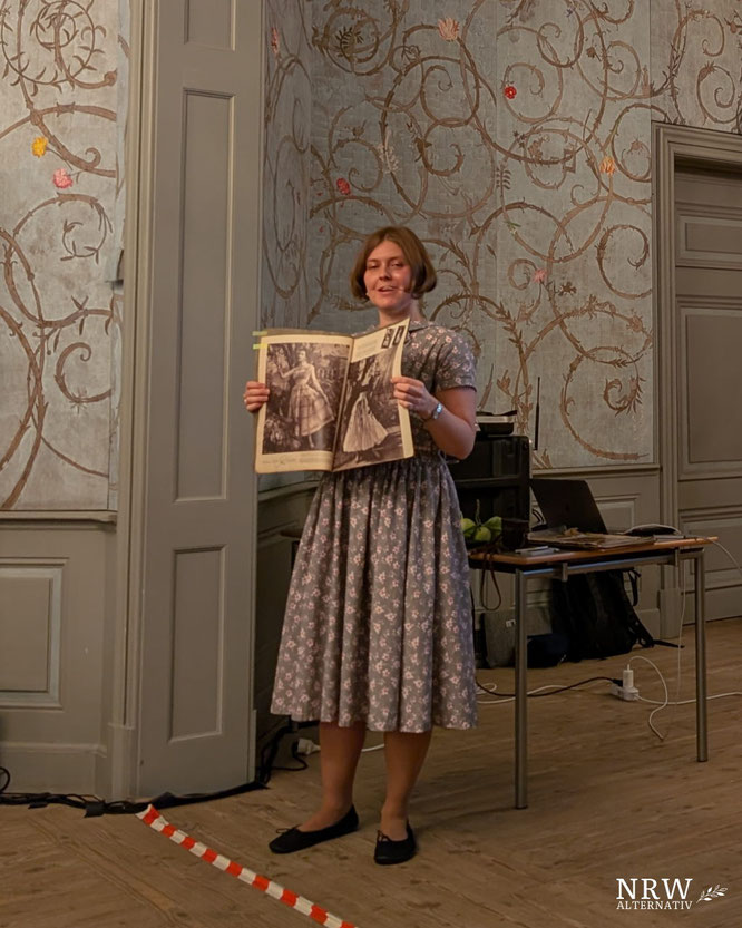 Frau, die eine aufgeschalgene Zeitung hochhält.