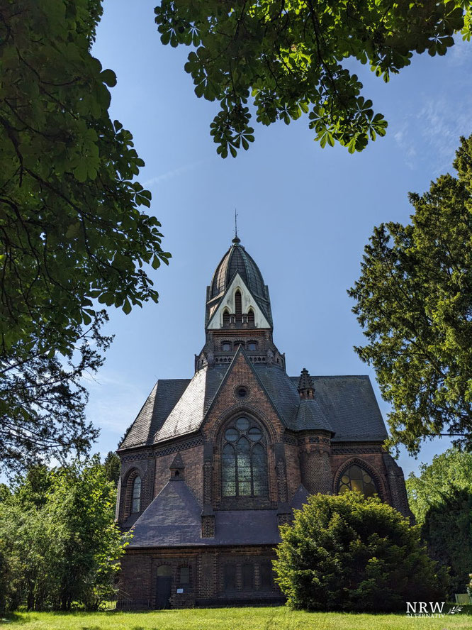 Ein altes Gebäude zwischen grünen Bäumen.