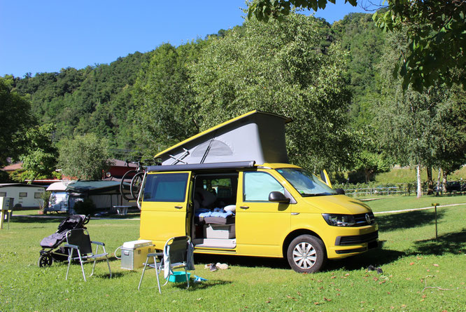 Campingplatz mit Wohnmobil bzw. VW-Bus. Ein Kinderwagen im Hintergrund zeigt, dass es ums Reisen mit Baby geht. Mama-Blog patschehand.de