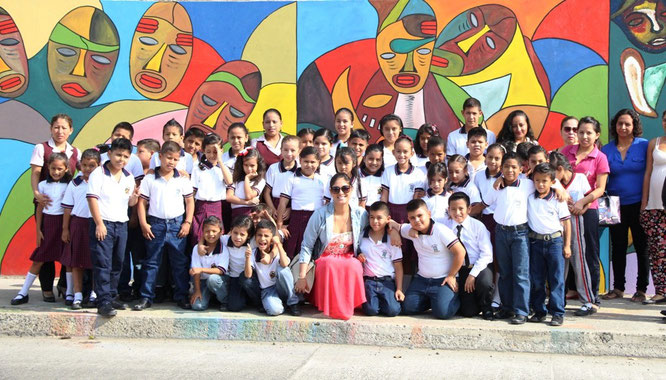 Estudiantes y profesores de la Escuela Jean Peaget posan delante del mural plasmado en su local. Manta, Ecuador.
