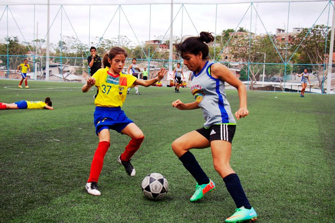 Dos jóvenes damas disputan un balón de fútbol durante un encuentro de campeonato. Manta, Ecuador.