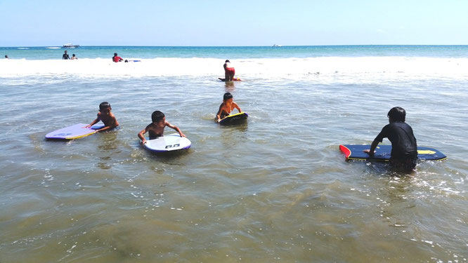 Niños practican bodyboard frente a la Playa el Murciélago. Manta, Ecuador.