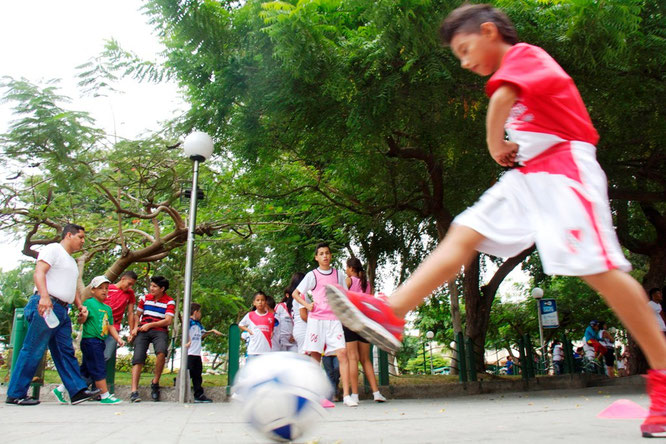 Jugando fútbol el Día del Deporte junto al parque central. Manta, Ecuador.